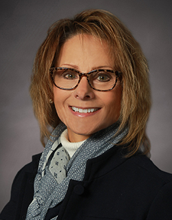 headshot of woman wearing suit and glasses