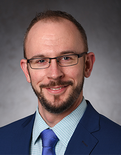 headshot of man wearing suit and glasses