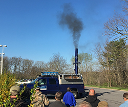 men watching smoke rise from stack of blue truck
