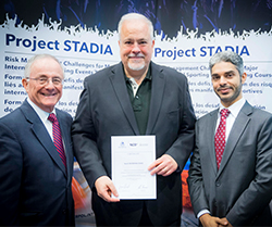 three men standing in front of project stadia signage